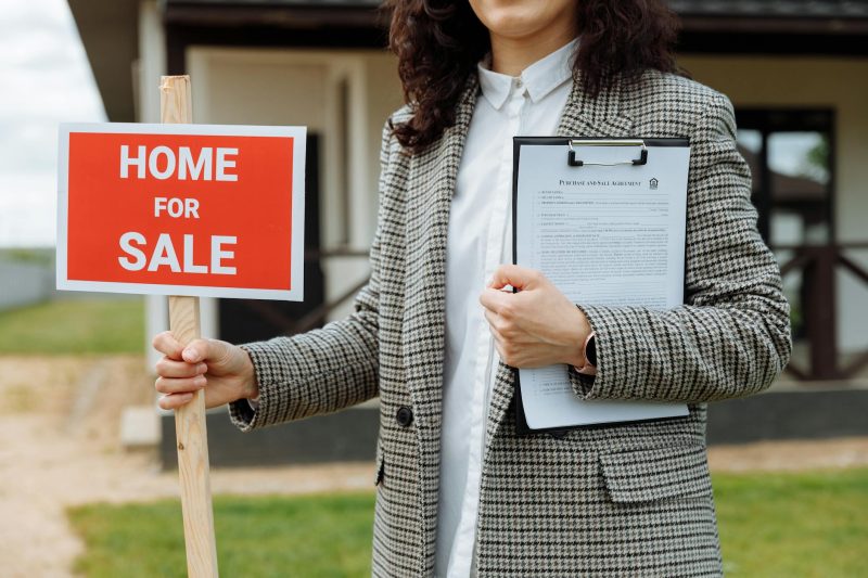 Home 14 A real estate agent holding a home for sale sign and clipboa 1779814844